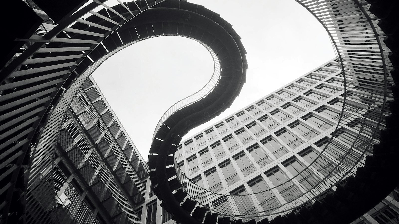Black and white view looking up a spiral staircase, its curved geometry suggesting movement and change