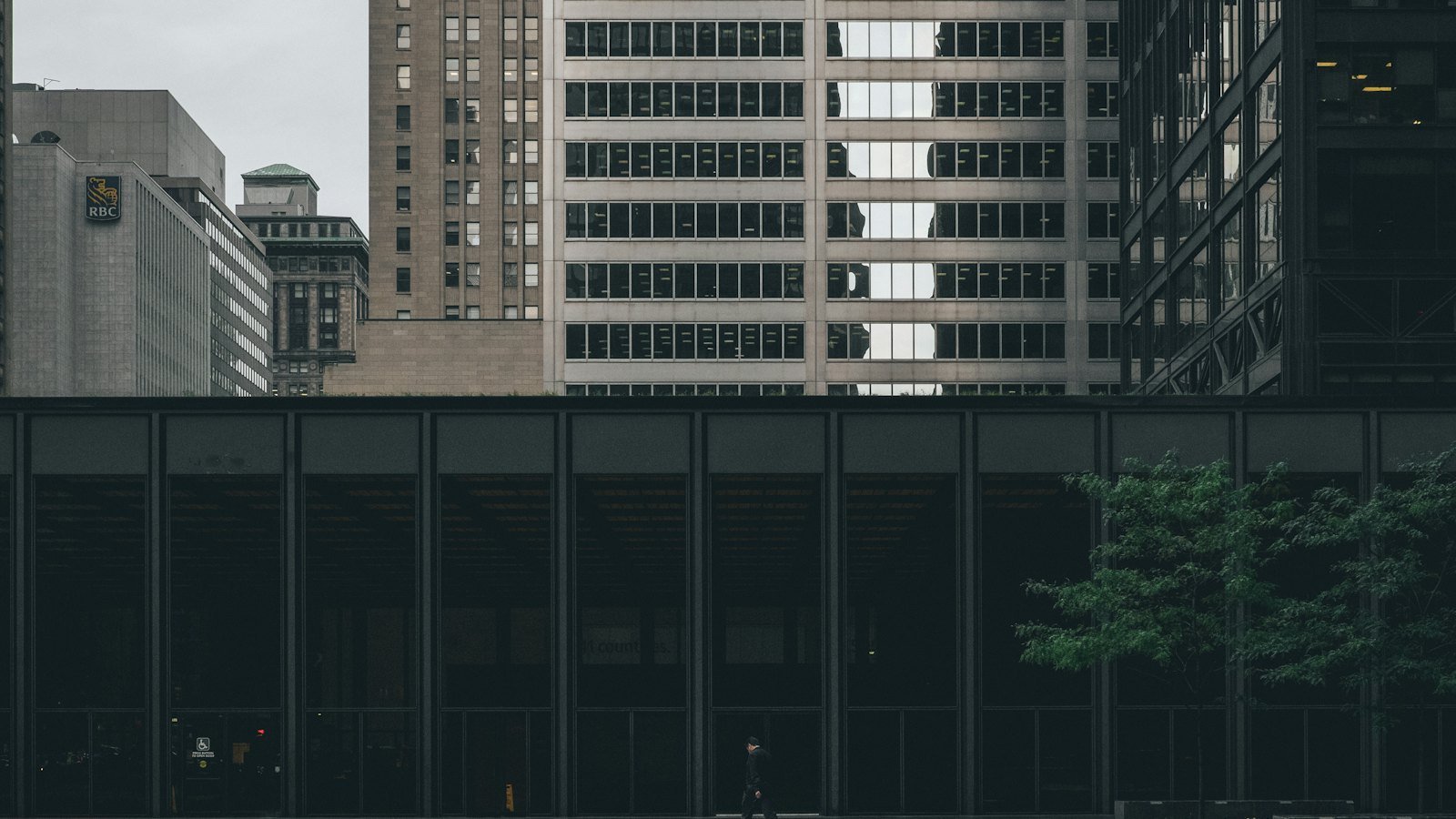 A businessperson in a suit walking past a modern glass office building