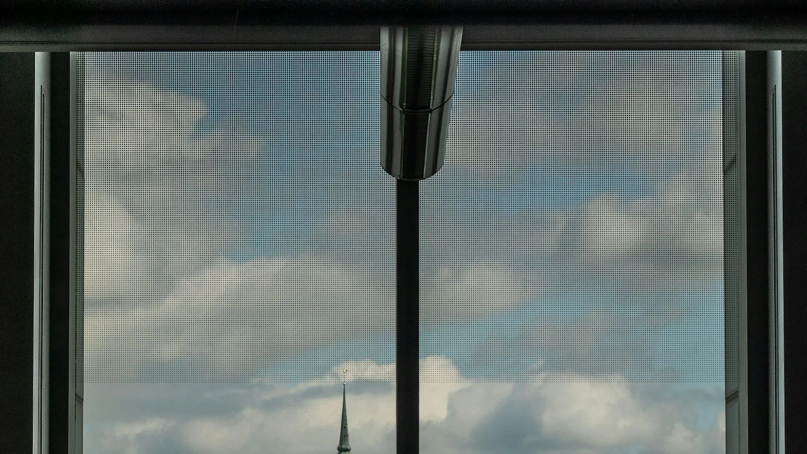 An empty armchair facing a tall window that overlooks a river and an old city skyline