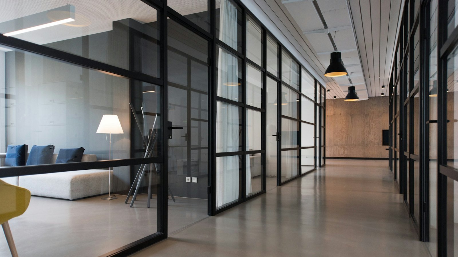 Empty modern office corridor lined with glass-panel doors and partitions