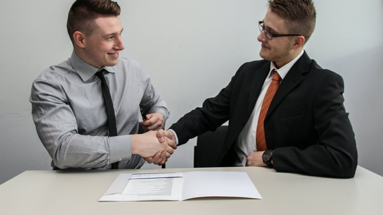 Two executives shaking hands in a bright office after agreeing a search mandate